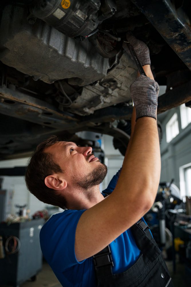 Male mechanic working on car in the auto repair shop<br />
